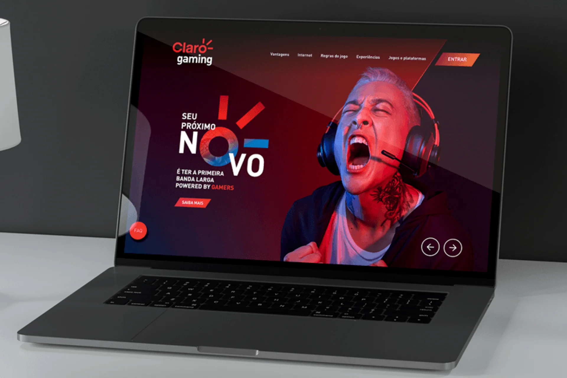 Laptop mostrando site Claro Gaming com gamer gritando, fone e layout vermelho.